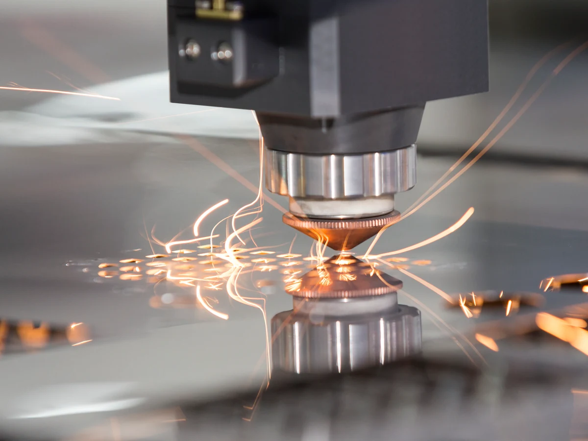 A laser cutting sheet metal with sparks around the cutting head